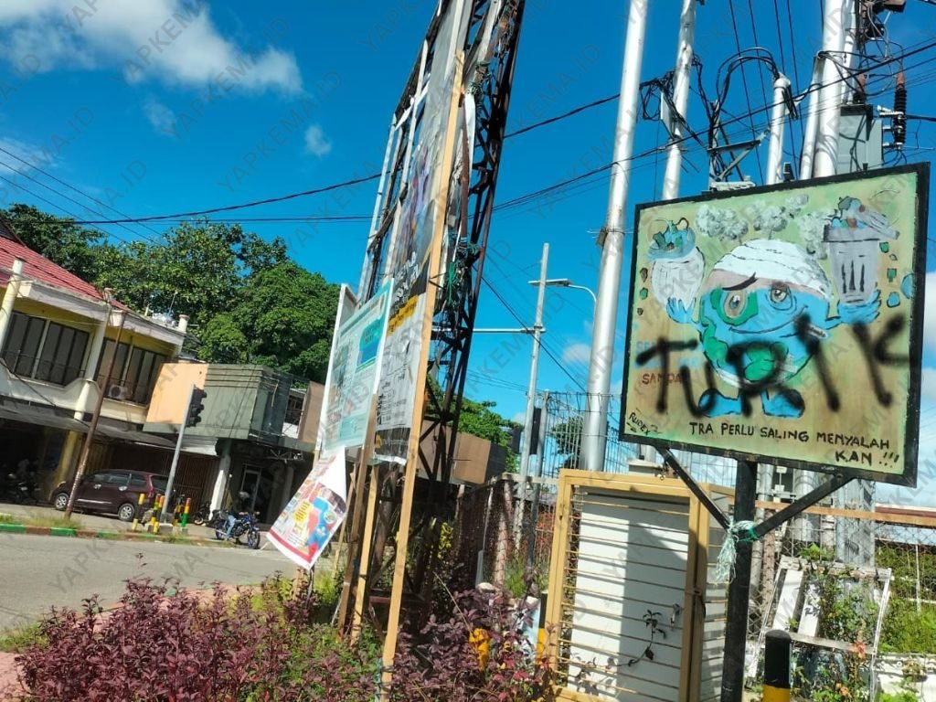 Poster kampanye tentang lingkungan di perempatan Kusuma, Karang Mulia, Nabire, yang sudah lama terpasang, tampak dicoret-coret dan tersisih di antara baliho-baliho besar lainnya. (Dok. Pribadi)