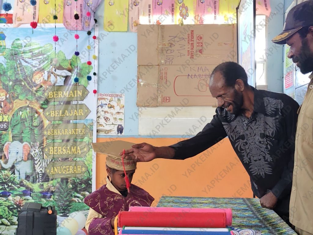 Kepala Dinas Dikpora Kabupaten Dogiyai, David Goo, melakukan prosesi pemindahan tali toga peserta didik pada acara Pelepasan TK PAUD Anugerah Ekemanida.(Dok. Yapkema)