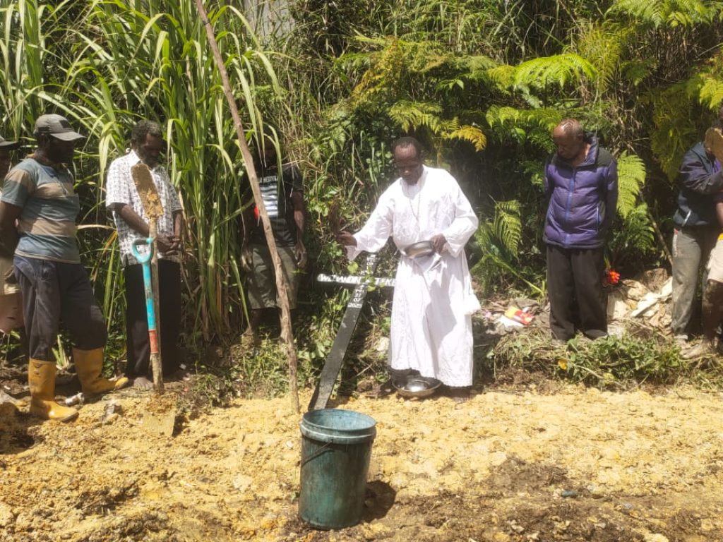 Pewarta sedang memberkati salib Weliandina pada ujung ibadah pemakaman