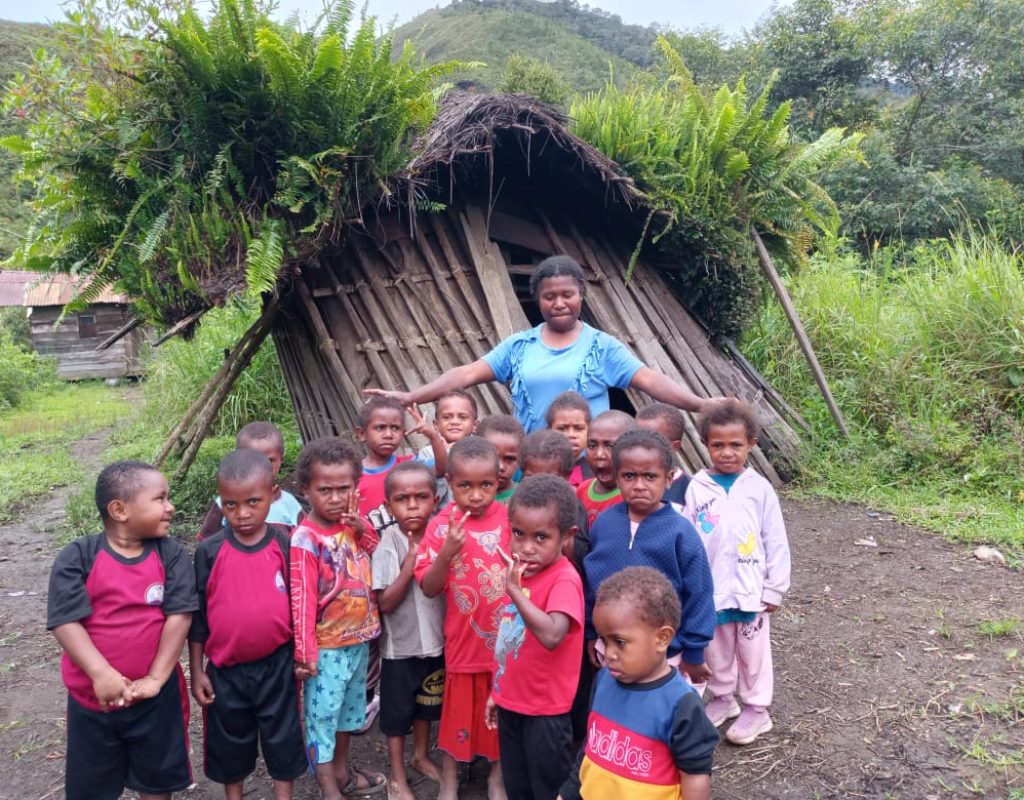 Kegiatan murid TK PAUD Anugerah Ekemaninda melihat rumah adat suku Mee dan pakaian adat pria suku Mee